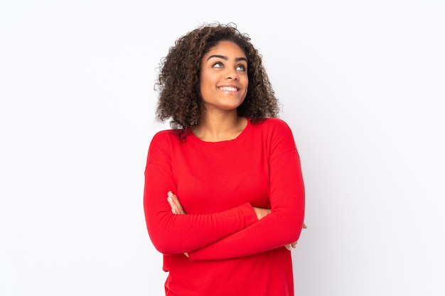 Joven mujer afroamericana en la pared mirando hacia arriba mientras sonríe