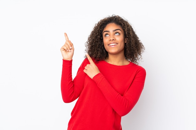 Joven mujer afroamericana en la pared señalando con el dedo índice una gran idea