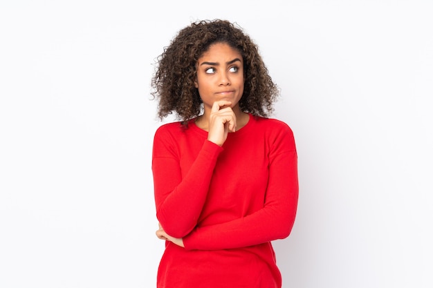 Joven mujer afroamericana en pared teniendo dudas y pensamiento