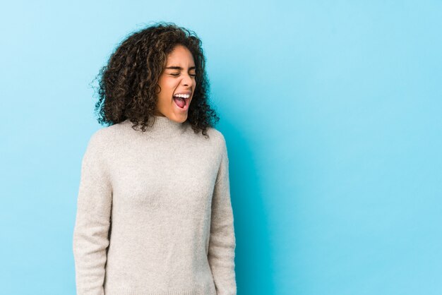 Joven mujer afroamericana de pelo rizado gritando hacia un espacio de copia