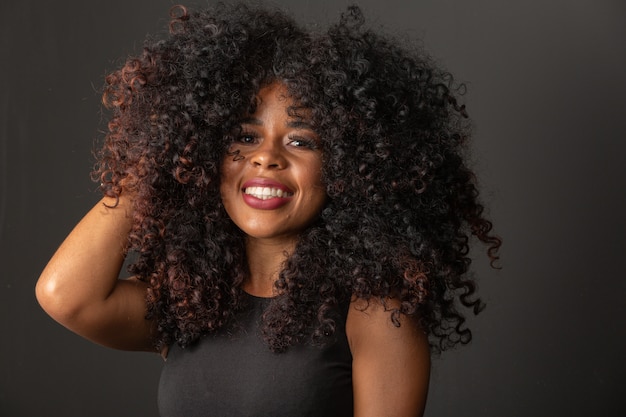 Joven mujer afroamericana con pelo rizado y sonriente. Linda chica afro con cabello rizado sonriendo