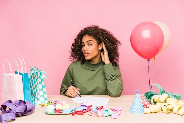 Joven mujer afroamericana planeando un cumpleaños tratando de escuchar un chisme.