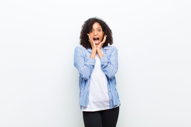 Joven mujer afroamericana que se siente sorprendida y emocionada, riendo, asombrada y feliz por una sorpresa inesperada