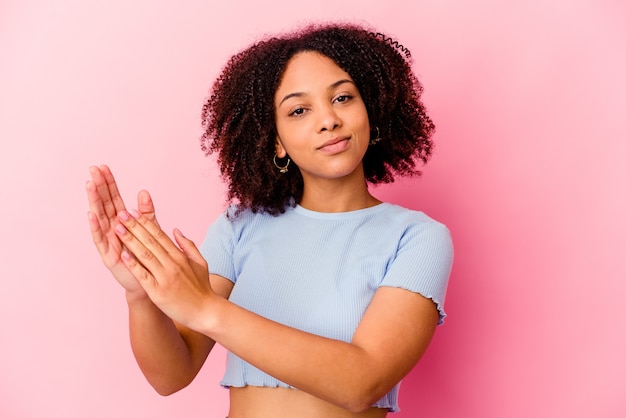 Joven mujer afroamericana de raza mixta aislada sintiéndose enérgica y cómoda, frotándose las manos con confianza.