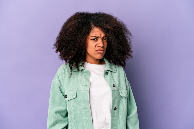 Joven mujer afroamericana rizada aislada en púrpura cara triste, seria, sintiéndose miserable y disgustada.