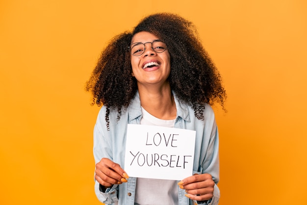 Joven mujer afroamericana rizada sosteniendo un cartel de amor a sí mismo