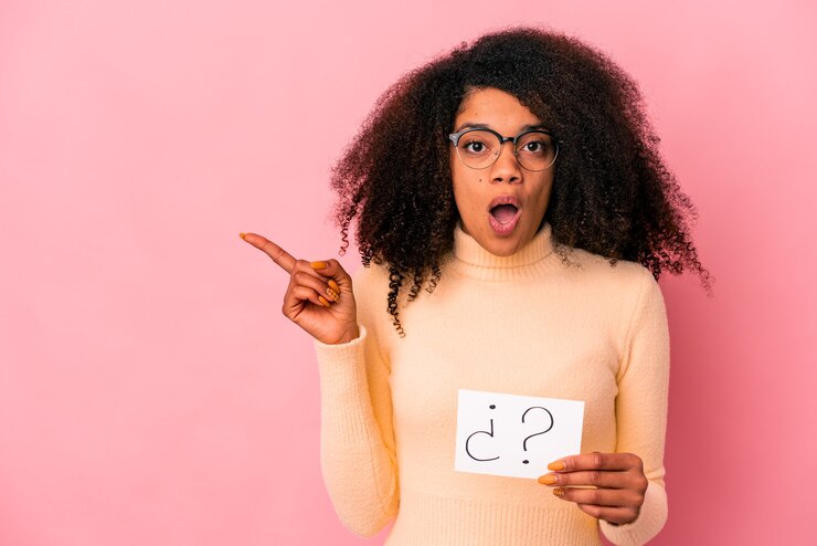 Foto joven mujer afroamericana rizada sosteniendo un interrogatorio en un cartel apuntando hacia el lado