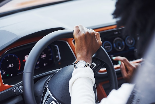 Joven mujer afroamericana se sienta dentro del coche nuevo y moderno.