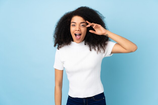 Joven mujer afroamericana sobre pared aislada se ha dado cuenta de algo y tiene la intención de la solución