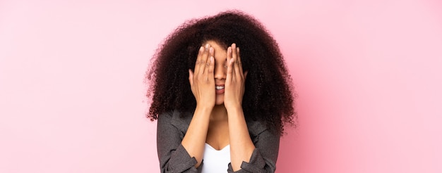 Joven mujer afroamericana sobre pared aislada que cubre los ojos con las manos