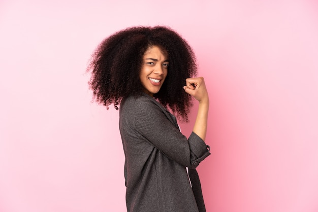 Joven mujer afroamericana sobre pared celebrando una victoria