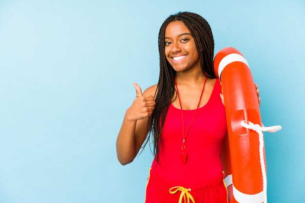 Joven mujer afroamericana socorrista aislado sonriendo y levantando el pulgar hacia arriba