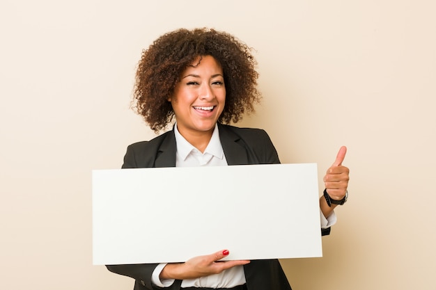 Joven mujer afroamericana sosteniendo un cartel sonriendo y levantando el pulgar