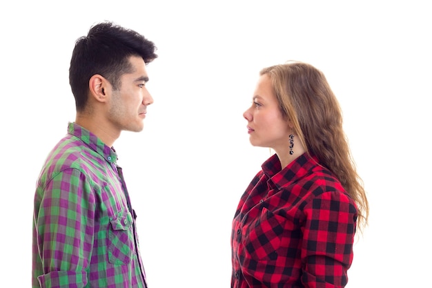 Joven mujer agradable con cabello castaño largo y hombre guapo con camisas a cuadros mirándose el uno al otro