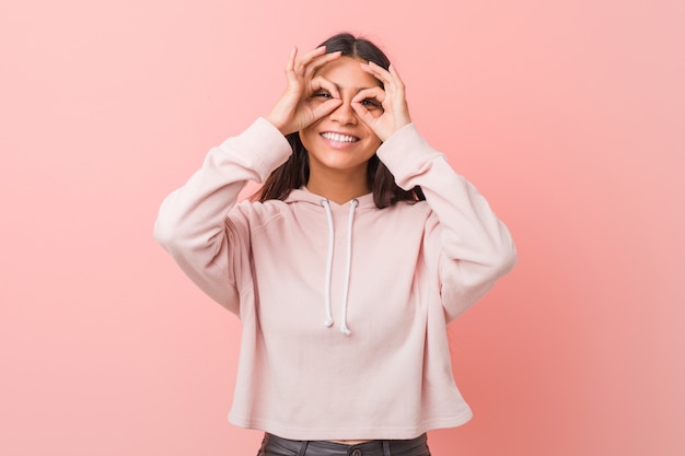 Joven mujer árabe bonita con un look deportivo informal que muestra signo bien sobre los ojos