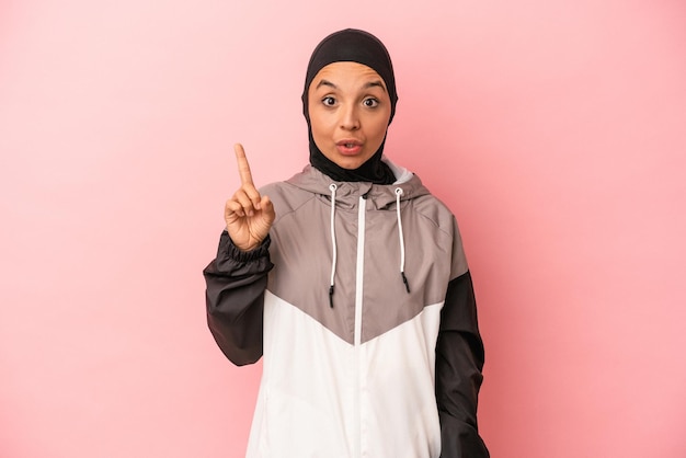 Joven mujer árabe con burka deportiva aislada de fondo rosa con una gran idea de concepto de creatividad