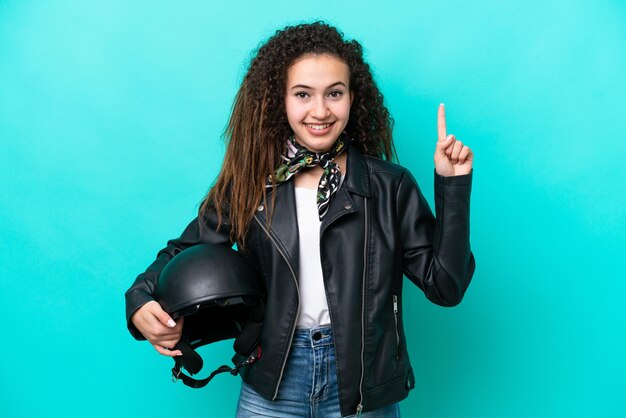 Joven mujer árabe con un casco de motocicleta aislado de fondo azul señalando una gran idea