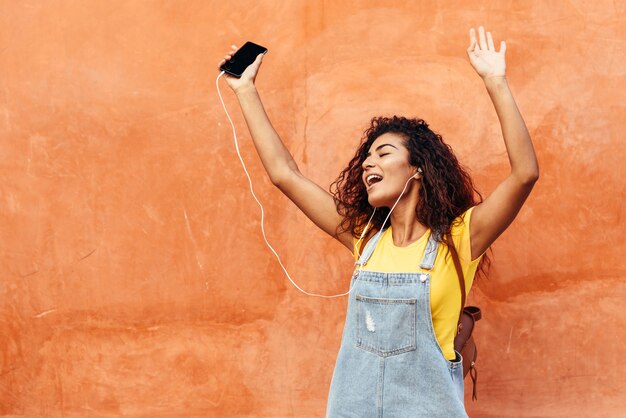 Joven mujer árabe escuchando música con auriculares al aire libre