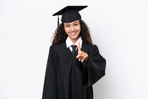 Joven mujer árabe graduada de la universidad aislada de fondo blanco mostrando y levantando un dedo