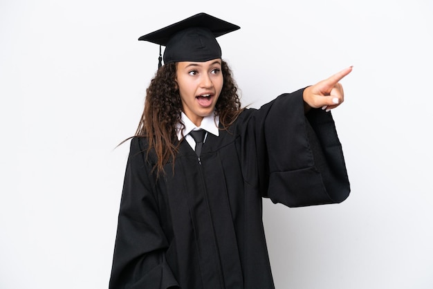 Joven mujer árabe graduada universitaria aislada de fondo blanco apuntando hacia otro lado