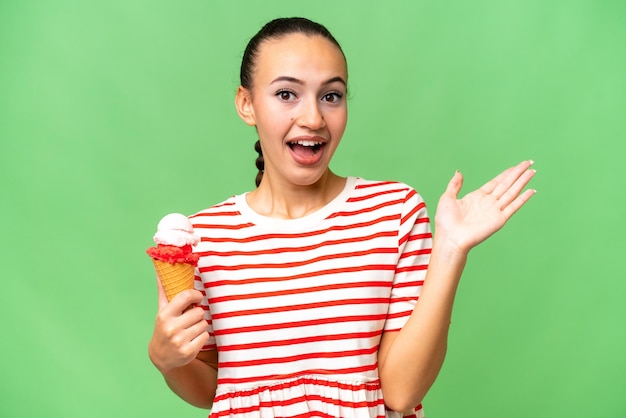 Joven mujer árabe con un helado de cucurucho sobre un fondo aislado con una expresión facial conmocionada