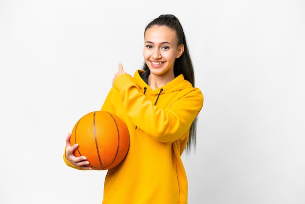 Joven mujer árabe jugando baloncesto sobre fondo blanco aislado apuntando hacia atrás