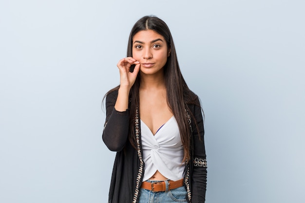 Joven mujer árabe natural y bonita con los dedos en los labios guardando un secreto.