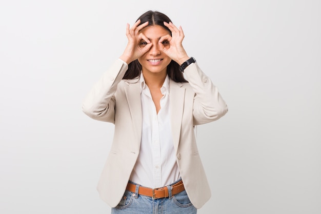 Joven mujer árabe de negocios aislada contra un fondo blanco que muestra signo bien sobre los ojos