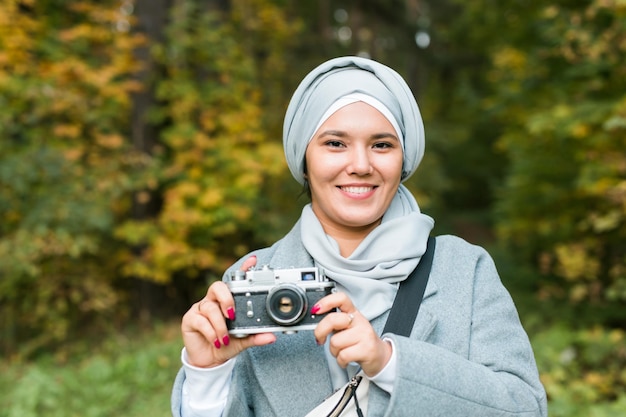 Joven mujer árabe con pañuelo hijab fotografiando con un teléfono inteligente en el parque. Chica musulmana moderna