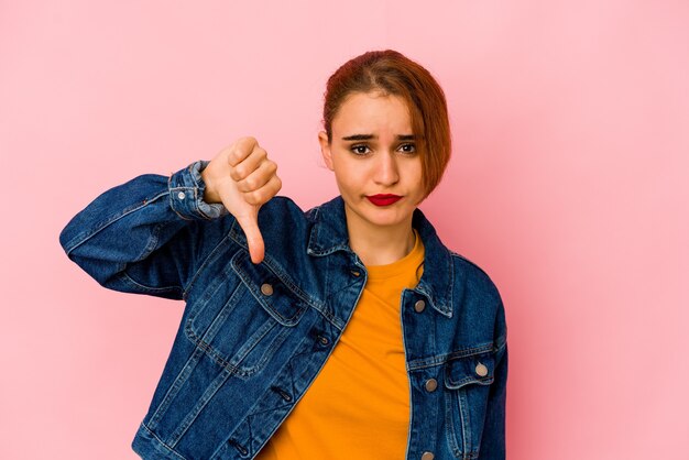 Joven mujer árabe de raza mixta mostrando el pulgar hacia abajo, concepto de decepción.