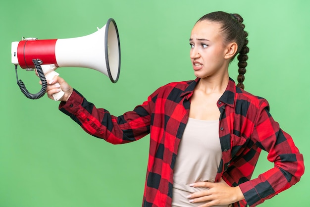 Joven mujer árabe sobre un fondo aislado sosteniendo un megáfono con expresión estresada