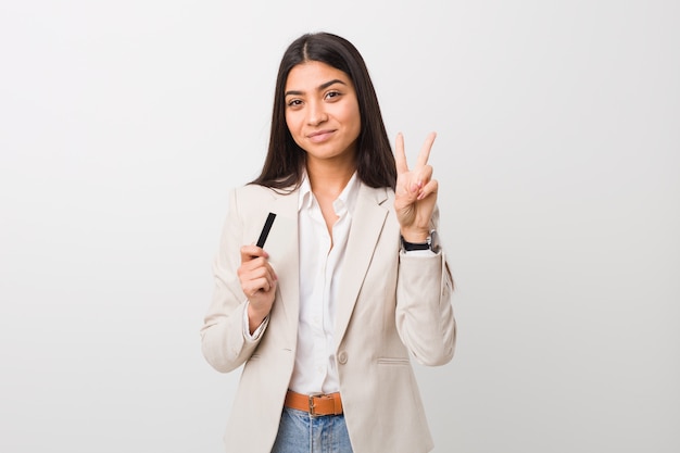 Joven mujer árabe con una tarjeta de crédito que muestra el número dos con los dedos.