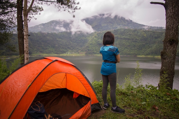 Joven mujer asiática acampar o hacer un picnic en el lago del bosque.