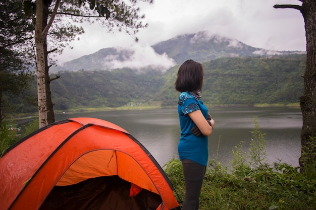 Joven mujer asiática acampar o hacer un picnic en el lago del bosque.