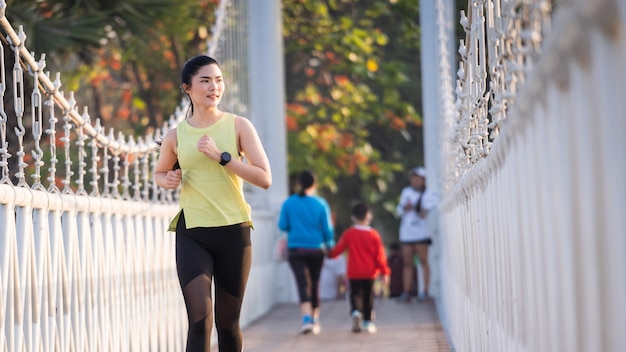 Una joven mujer asiática atleta corredor trotar en el estadio de la ciudad en la mañana soleada para mantener un estilo de vida saludable y fitness. Corredor activo y saludable para correr al aire libre. Deportes y Recreación