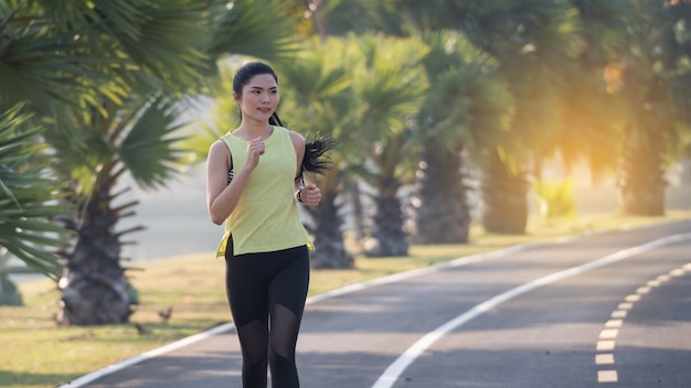 Una joven mujer asiática atleta corredor trotar en el estadio de la ciudad en la mañana soleada para mantener un estilo de vida saludable y fitness. Corredor activo y saludable para correr al aire libre. Deportes y Recreación