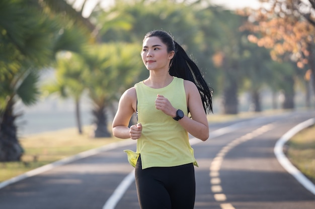 Una joven mujer asiática atleta corredor trotar en el estadio de la ciudad en la mañana soleada para mantener un estilo de vida saludable y fitness. Corredor activo y saludable para correr al aire libre. Deportes y Recreación