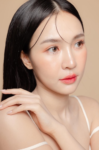 Joven mujer asiática de belleza de pelo largo con estilo de maquillaje coreano en la cara y piel perfecta sobre fondo beige aislado Tratamiento facial Cosmetología cirugía plástica