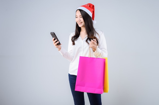 Foto joven, mujer asiática, con, bolsas de compras, y, gorro de santa