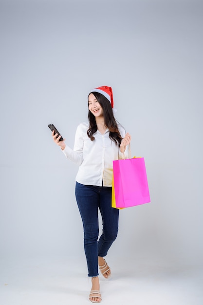 Foto joven, mujer asiática, con, bolsas de compras, y, gorro de santa