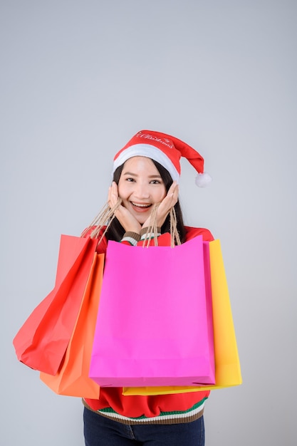 Foto joven, mujer asiática, con, bolsas de compras, y, gorro de santa