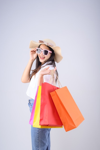 Joven mujer asiática con bolsas de compras y sombrero de paja