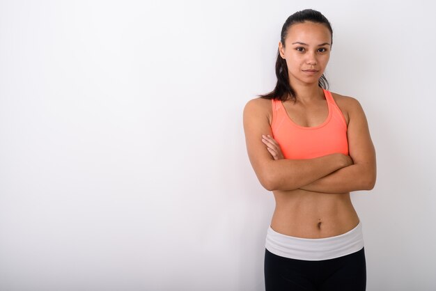 Joven mujer asiática con los brazos cruzados, listo para el gimnasio contra el espacio en blanco