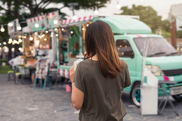 Joven mujer asiática caminando en el mercado de camiones de comida