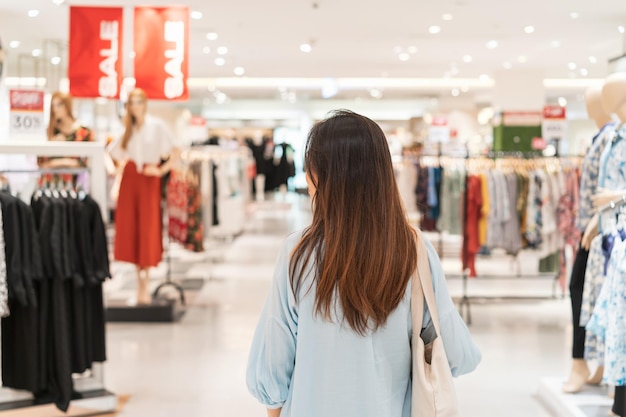 Joven mujer asiática caminando en la tienda de ropa en el centro comercial, concepto de estilo de vida de mujer