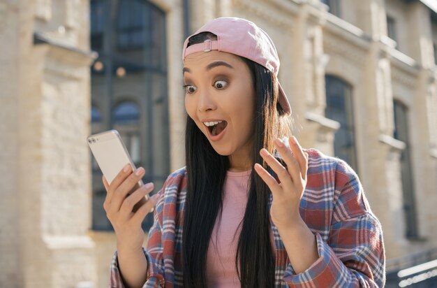 Joven mujer asiática emocionada con smartphone