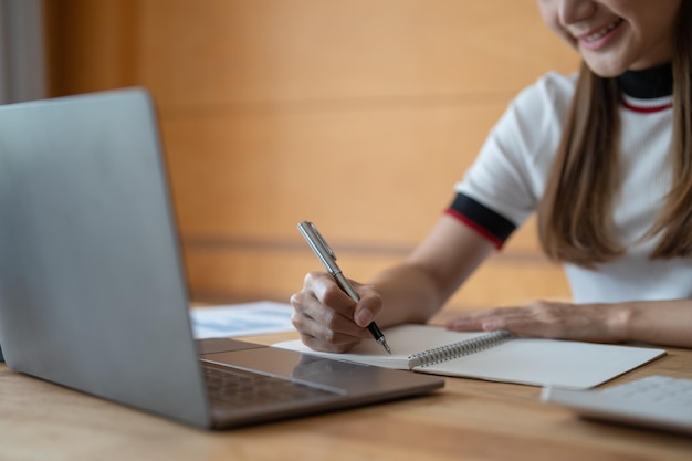 Joven mujer asiática escribiendo notas en un cuaderno viendo un curso de video de seminario web estudiante negro serio mirando una computadora portátil escuchando un estudio de conferencias en línea en el aprendizaje electrónico de la computadora