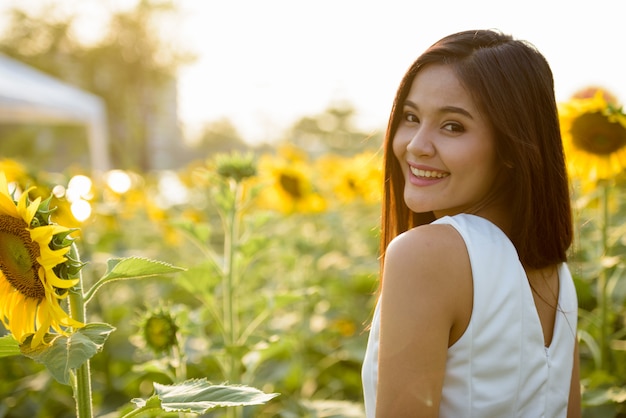 Joven mujer asiática feliz sonriendo y mirando hacia atrás en el campo