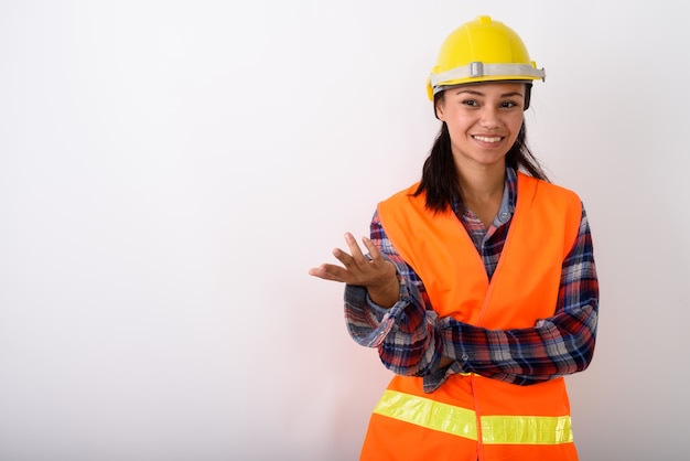 Foto joven mujer asiática feliz trabajador de la construcción sonriendo con el brazo levantado contra el espacio en blanco