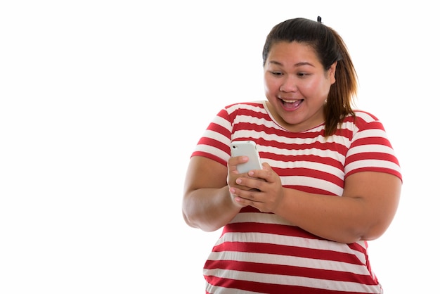 Joven mujer asiática gorda feliz sonriendo mientras usa el teléfono móvil